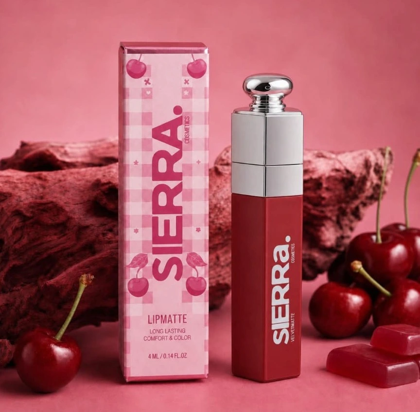Sierra Rae Velvet Matte lipmatte tube with chrome cap beside its cherry-print gingham box, styled with fresh cherries