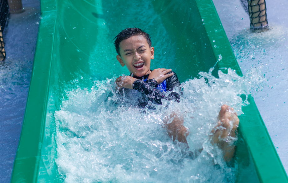 Child laughing on a green water slide